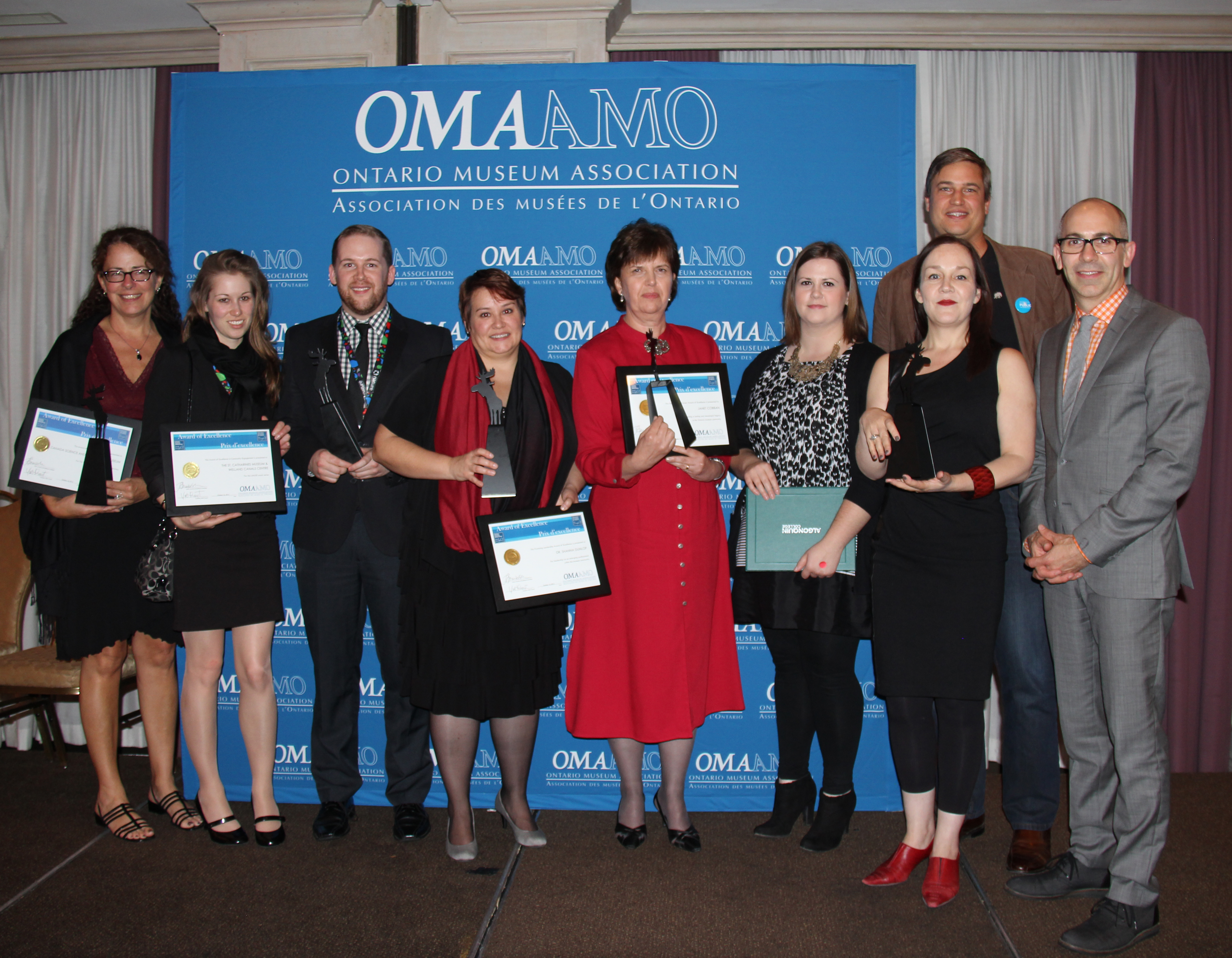 Group photo of Awards of Excellence recipients in front of OMA banner