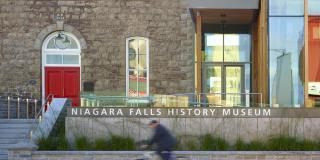 Cyclists passing the front of the Niagara Falls History Museum on Lundy's Lane