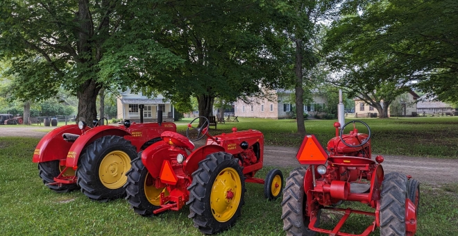 Three red tractors parked in the historic village